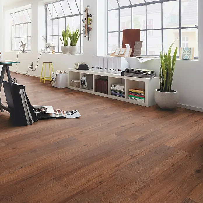 b!design Vinylboden SPC - Eiche Avignon, Landhausdiele, 1.220 x 182 x 4,3 mm - Warmer, brauner Laminatboden mit natürlicher Holzmaserung in einem hellen, modernen Büro mit großen Fenstern.