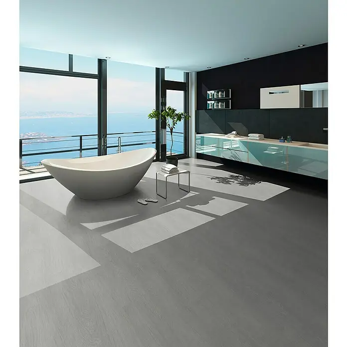 b!design Vinylboden SPC - Eiche Pilatus, Landhausdiele, 1.220 x 182 x 4,3 mm - Grauer Holzoptikboden in einem modernen Badezimmer mit Meerblick. Der Boden zeigt natürliche Holzmaserungen und reflektiert Sonnenlicht.