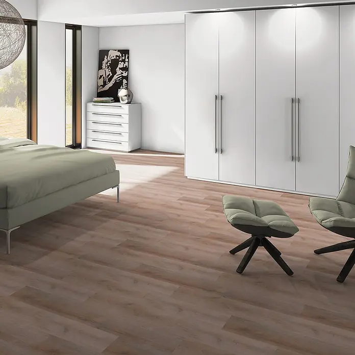 b!design Vinylboden SPC - Western Eiche, Landhausdiele, 1.220 x 182 x 4,3 mm - Breitdieliger, hellbrauner Holzboden mit sichtbarer Maserung, in einem modernen Schlafzimmer unter Bett und Sitzgelegenheiten.