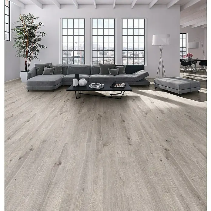 Laminado Valkyrie - 1.285 x 192 x 8 mm, Gris, AC4 - Suelo de madera gris claro con veta natural en un salón moderno.