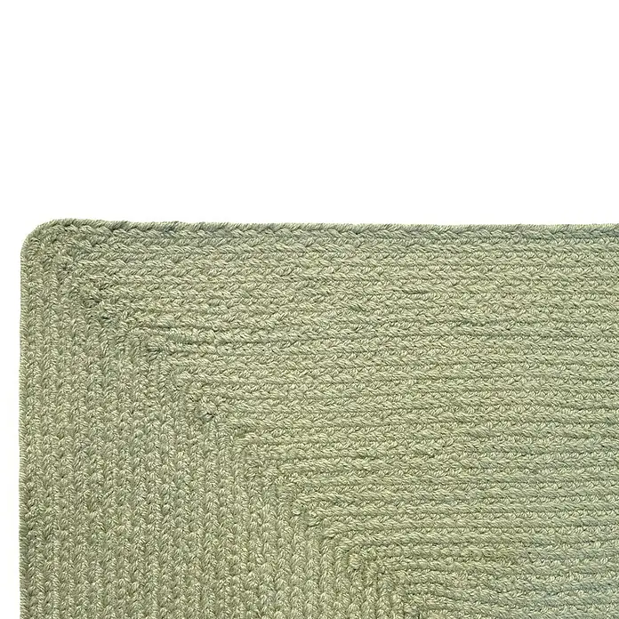 Alfombra exterior In/Out Ebro - Verde, 110 x 60 cm, 100% Polietileno - Esquina de alfombra trenzada verde claro. Textil tejido a mano con textura distintiva.