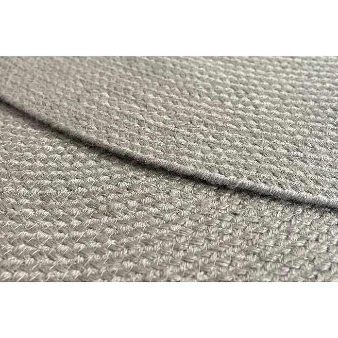 Alfombra exterior In/Out Ebro - Plata, Diámetro: 120 cm, 100% Polietileno - Primer plano de tejido gris trenzado con superficie texturizada y una costura.