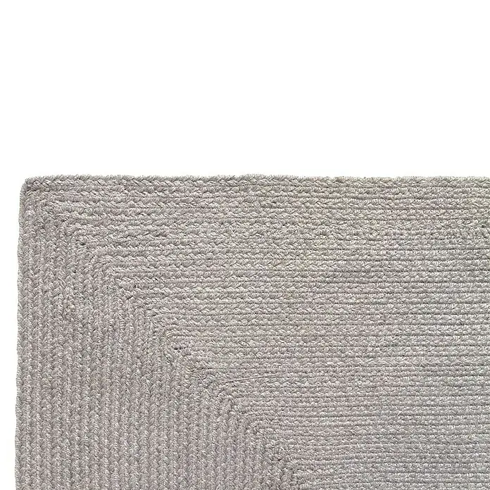 Alfombra exterior In/Out Ebro - Plata, 110 x 60 cm, 100% Polietileno - Esquina de alfombra trenzada gris con textura de tejido apretado.