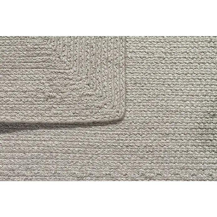 Alfombra exterior In/Out Ebro - Plata, 110 x 60 cm, 100% Polietileno - Primer plano de una alfombra trenzada gris claro mostrando su textura tejida y una esquina.