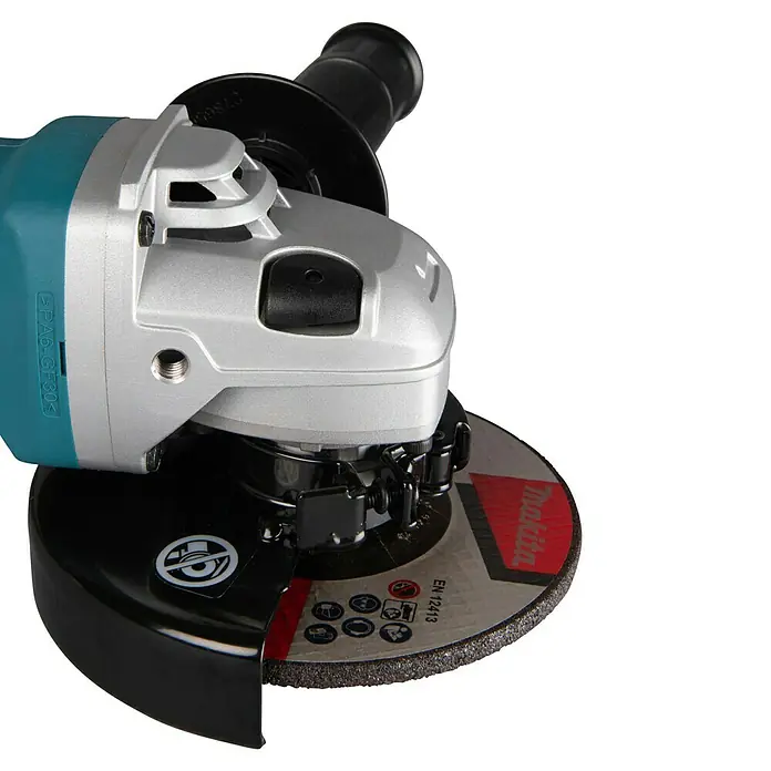 Makita Elektro-Winkelschleifer 9565CR - 1.400 W, 11.000 U/min - Nahaufnahme eines Winkelschleifers mit türkisfarbenem und silbernem Gehäuse, schwarzem Griff und einer dunkelgrauen Trennscheibe mit Makita-Logo und Sicherheitssymbolen.