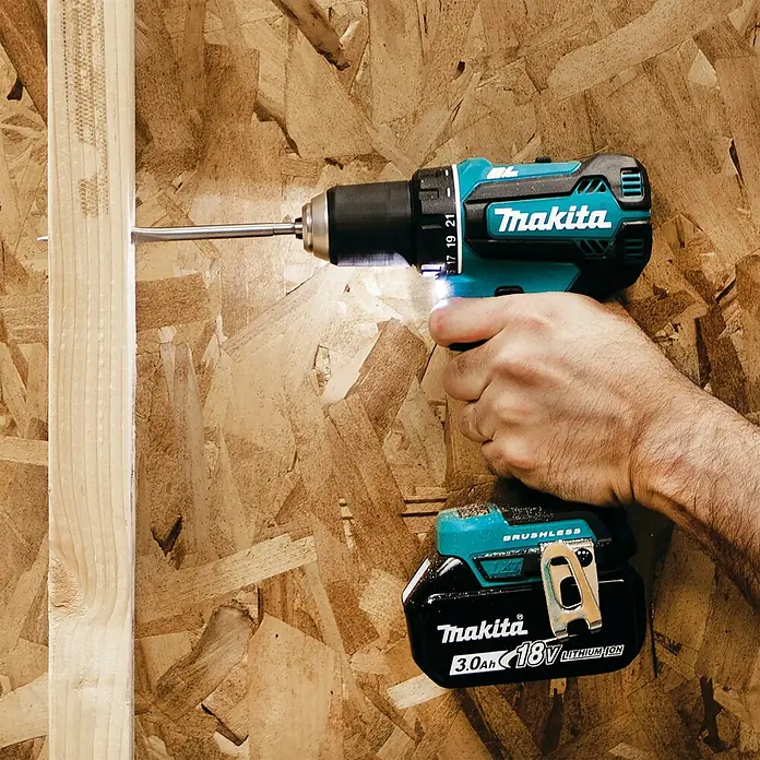Makita LXT 18V Akku-Bohrschrauber-Set DDF485RFJ - 18 V, 2 Akkus, 50 Nm - Eine Hand bedient einen türkis-schwarzen Makita Akku-Bohrschrauber, der eine Schraube in einen Holzbalken vor einer OSB-Wand eindreht.