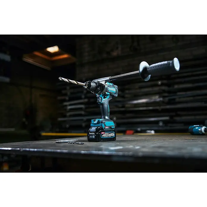 Makita XGT 40V max. Akku-Schlagbohrschrauber HP001GD201 - 40 V, 2 Akkus, 2,5 Ah, 41 Nm - Türkis-schwarze Makita Akku-Schlagbohrmaschine mit langem Griff und Bohrer auf einer dunklen Werkbank.