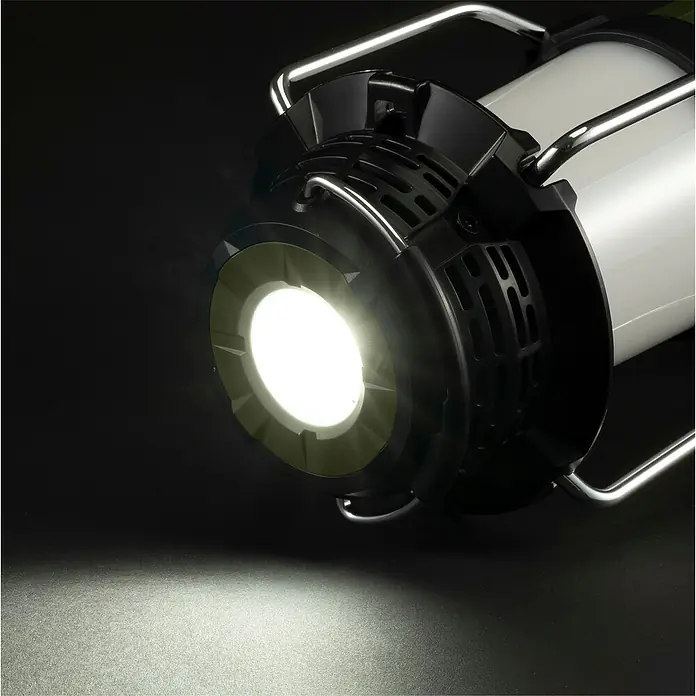 Makita LXT 18V Radio de batería con linterna DMR056 - 18 V, Sin batería, Flujo luminoso: 310 lm - Una linterna LED blanca y negra con asas cromadas, que proyecta una luz blanca brillante sobre una superficie oscura.