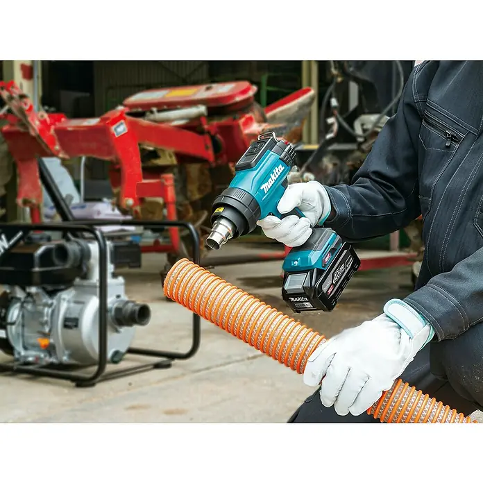 Makita XGT 40V max. Akku-Heißluftgebläse HG001G - 40 V, Ohne Akku, Temperaturbereich: 0 °C - 600 °C - Eine Person erhitzt mit einer türkisen Makita Akku-Heißluftpistole einen orangefarbenen Wellschlauch. An der Pistole ist ein Makita 40V Akku.