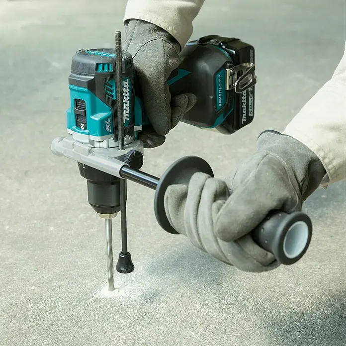 Makita LXT 18V Akku-Schlagbohrschrauber DHP492RTJ - 18 V, 2 Akkus, 5 Ah, 130 Nm - Türkis-schwarzer Makita Akku-Bohrhammer, von behandschuhten Händen gehalten, bohrt in eine Betonoberfläche.