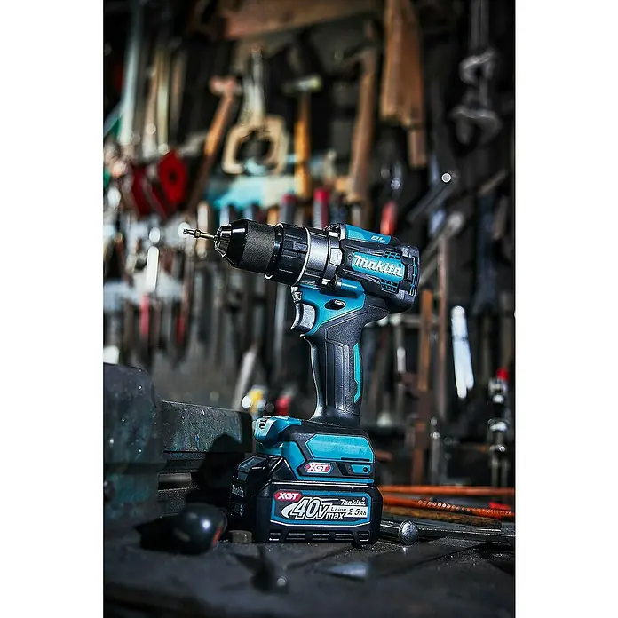 Makita XGT 40V max. Akku-Schlagbohrschrauber HP001GZ - 40 V, Ohne Akku - Makita Akku-Bohrschrauber in Türkis und Schwarz mit Akku auf einer Werkbank in unaufgeräumter Werkstatt.