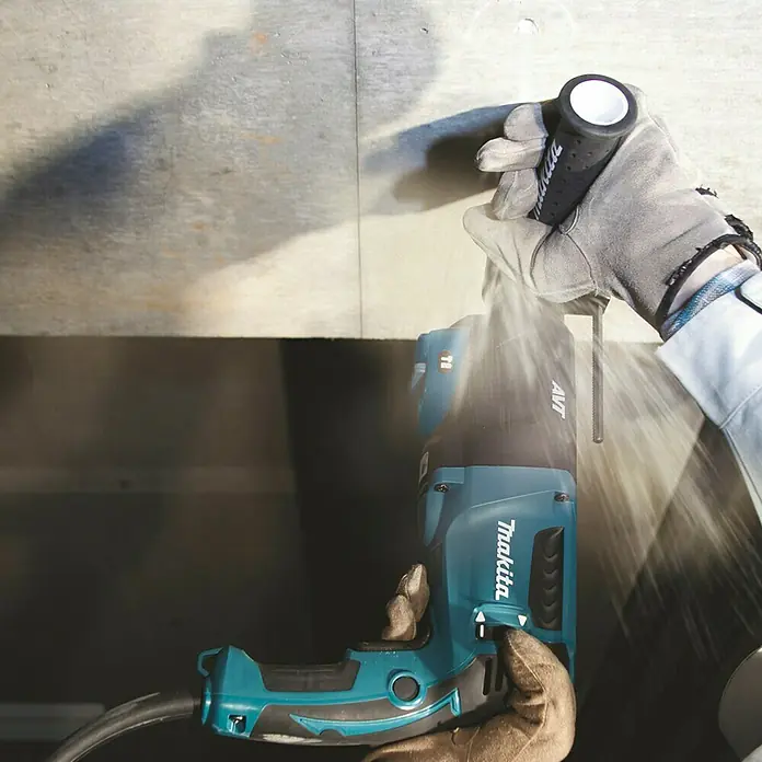 Makita Kombihammer HR2631FT13 - 800 W, 2,4 J, Schnellspannbohrfutter - Blauer und schwarzer Makita Bohrhammer im Einsatz, bohrt in eine helle Wand mit aufwirbelndem Staub.