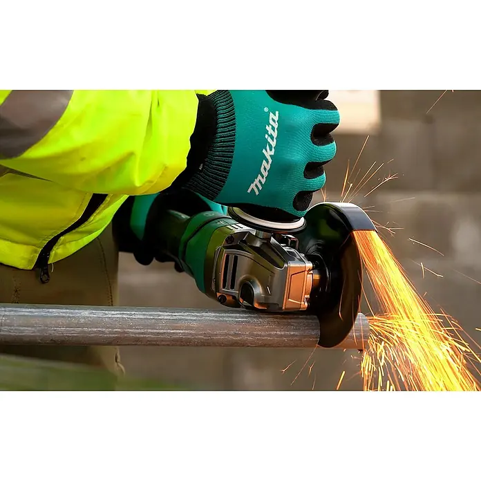 Makita XGT 40V max. Akku-Winkelschleifer GA050GZ - Ohne Akku, Durchmesser Scheibe: 125 mm - Makita Winkelschleifer, gehalten von Händen mit Makita-Handschuhen, schneidet Metallrohr und erzeugt Funken.