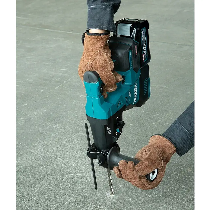 Makita XGT 40V max. Akku-Kombihammer HR003GM201 - 40 V, 2 Akkus, 4 Ah, 2,8 J - Eine Person in braunen Handschuhen benutzt einen türkisfarbenen und schwarzen Makita Akku-Bohrhammer, um in Beton zu bohren.