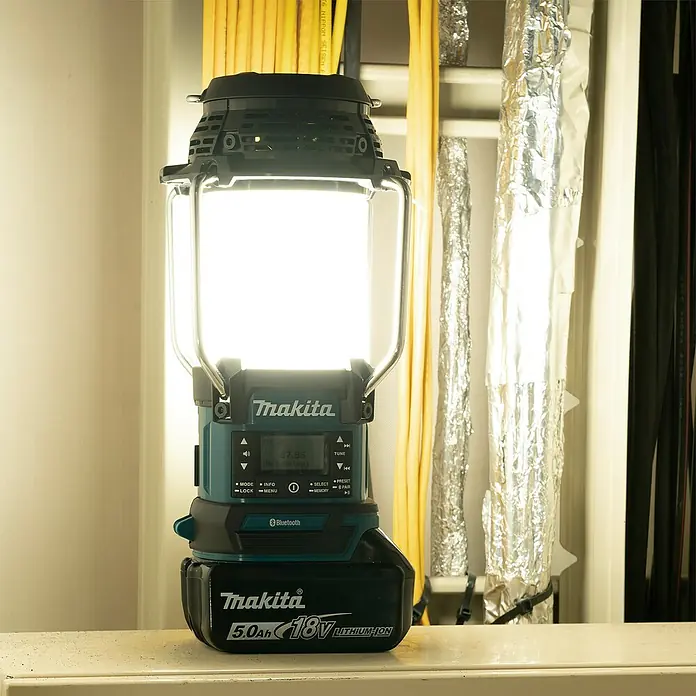 Makita LXT 18V Radio de batería con linterna DMR056 - 18 V, Sin batería, Flujo luminoso: 310 lm - Una linterna Makita negra y turquesa encendida con una batería de litio de 18V 5.0Ah, que muestra '87.55' en pantalla.