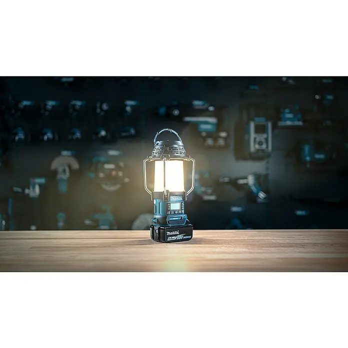 Makita LXT 18V Radio de batería con linterna DMR056 - 18 V, Sin batería, Flujo luminoso: 310 lm - Una linterna Makita encendida con batería sobre una superficie de madera en un taller difuminado.