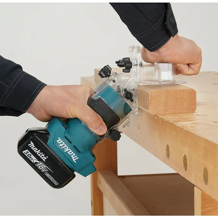 Makita LXT 18V Akku-Kantenfräser DRT52Z - 18 V, Ohne Akku, Leerlaufdrehzahl: 30.000 U/min - Eine Person benutzt einen türkis-schwarzen Makita Akku-Fräser mit 18V 3.0Ah Akku zum Holzfräsen auf einer Werkbank.