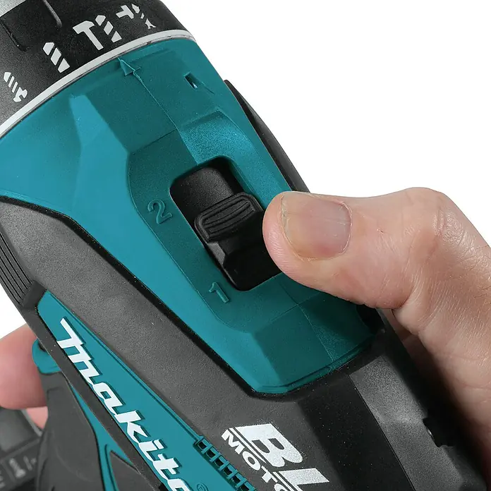 Makita LXT 18V Akku-Schlagbohrschrauber Quadroschrauber DTP141Z mit Schlagschraubfunktion - 18 V, Ohne Akku, 150 Nm - Nahaufnahme einer Hand, die den Zweigang-Wählschalter eines türkis-schwarzen Makita-Bohrers einstellt.
