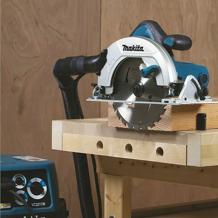 Makita Handkreissäge HS7601J - 1.200 W, Durchmesser Sägeblatt: 190 mm - Makita Handkreissäge auf Holzwerkbank, an VC3211M Staubsauger für Holzarbeiten angeschlossen.