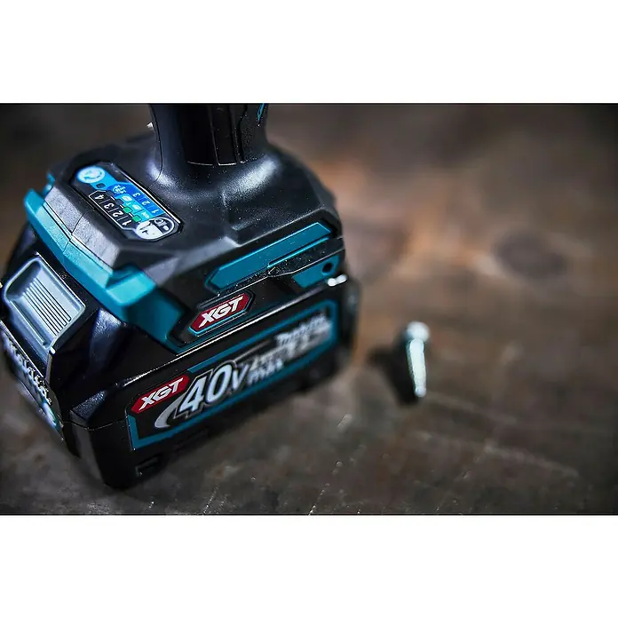 Makita XGT 40V max. Akku-Schlagschrauber TD001GZ - 40 V, Ohne Akku - Nahaufnahme eines schwarzen und türkisfarbenen Makita XGT 40V Akkus mit beleuchteten Ladeanzeigen, an ein Elektrowerkzeug angeschlossen.