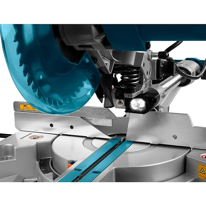Makita Kapp- & Gehrungssäge LS0815FLN - 1.400 W, Durchmesser Sägeblatt: 216 mm, 0 U/min - 5.000 U/min - Nahaufnahme einer Gehrungssäge mit blauem, durchsichtigem Sägeblattschutz, silbernem Unterbau, Schneidmechanismus und Arbeitsleuchte.