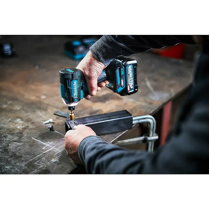 Makita XGT 40V max. Akku-Schlagschrauber TD001GD201 - 40 V, 2 Akkus, 2,5 Ah - Person nutzt einen türkis-schwarzen Makita 40V max Schlagschrauber, um eine Schraube in ein schwarzes Metallprofil zu drehen.