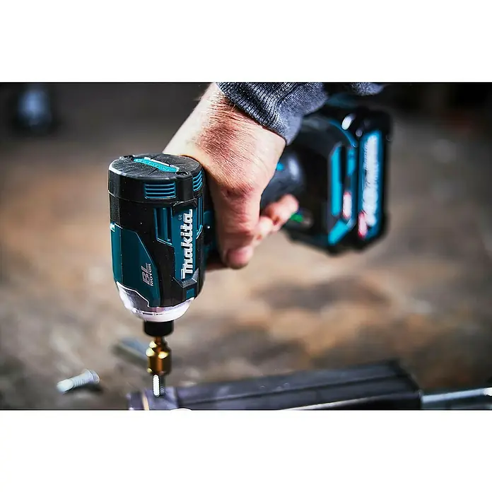 Makita XGT 40V max. Akku-Schlagschrauber TD001GD201 - 40 V, 2 Akkus, 2,5 Ah - Person hält einen türkis-schwarzen Makita Schlagschrauber, der eine Schraube in Metall eindreht.