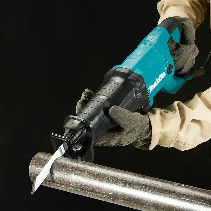Makita Säbelsäge JR3051TK - 1.200 W, Hublänge: 30 mm - Türkis-schwarze Makita Säbelsäge in behandschuhten Händen schneidet Metallrohr.