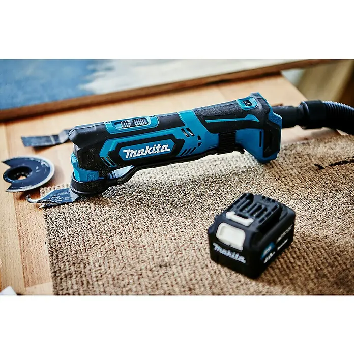 Makita CXT 12V max. Akku-Multifunktionswerkzeug TM30DZ - 12 V, Ohne Akku - Blau-schwarzes Makita Akku-Oszillierwerkzeug mit Zubehörklingen und Akku auf einer strukturierten Arbeitsfläche.