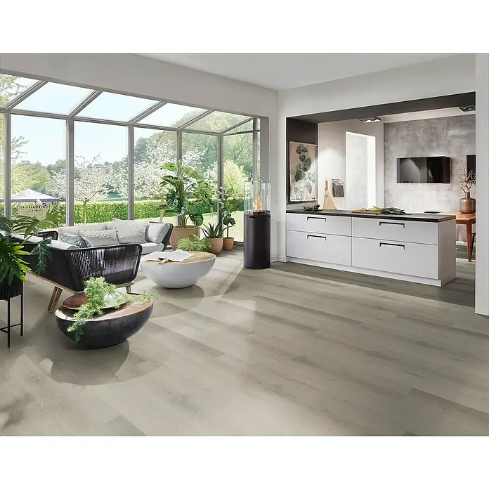 Fixed Vinylboden Plus - Teresina, Landhausdiele, 1.530 x 235 x 3 mm - Heller Holzoptik-Bodenbelag in einem offenen Wohn- und Küchenbereich mit großen Fenstern und Gartenblick.