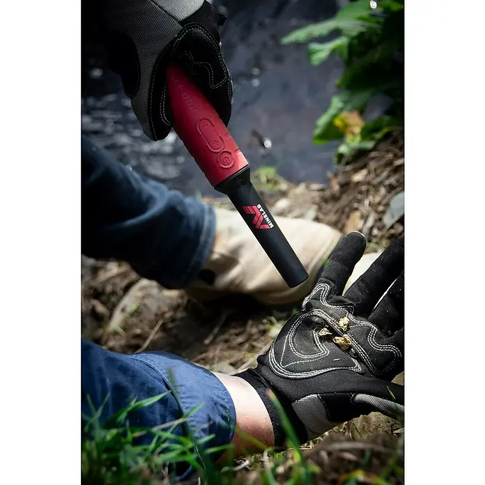 Minelab Metalldetektor PRO-FIND 40 Pinpoint - L x B x H: 50 x 50 x 250 mm - Roter Minelab Pro-Find Pinpointer, von einer behandschuhten Hand gehalten, zum Aufspüren von Goldnuggets.
