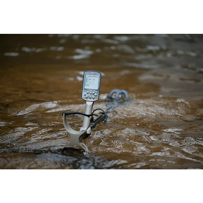 Minelab Metalldetektor X-TERRA ELITE - 3,7 V, 1 Akku, 5.100 mAh, L x B x H: 230 x 310 x 1.380 mm - Ein hellgrauer Metalldetektor mit schwarzer Spule im flachen, fließenden Wasser, aktiv suchend.