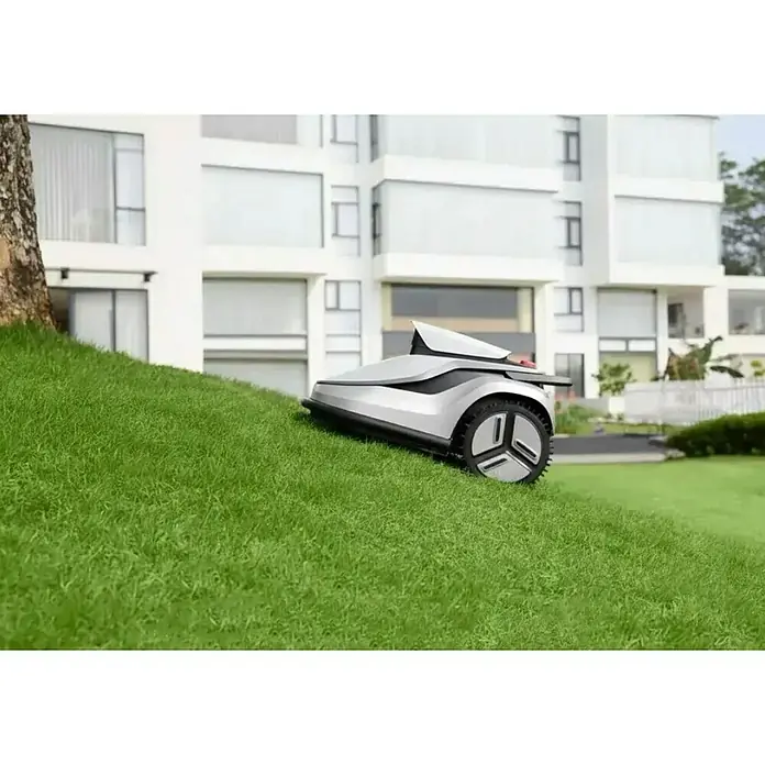 Terramow Mähroboter-Set V600 inkl. Garage - 600 m², Schnittbreite: 20,3 cm, Kamera-gestützte Navigation - Ein silber-schwarzer Mähroboter mit futuristischem Design, der an einem Hang neben einem Baum arbeitet.