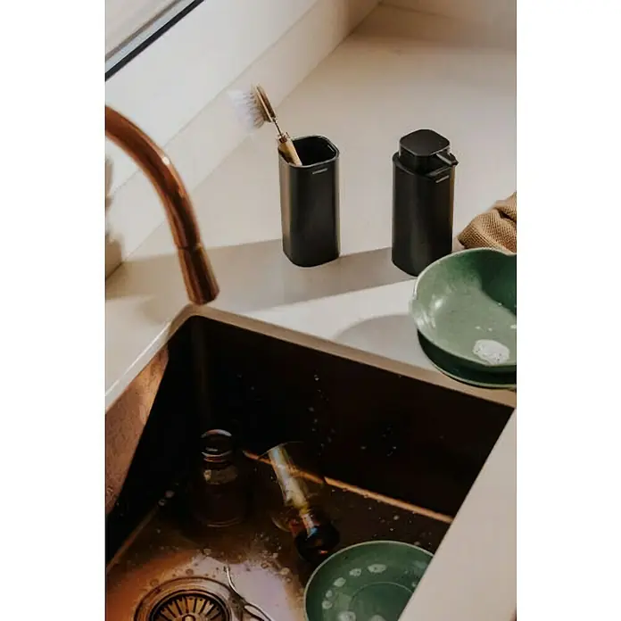 Cosmic Portacepillos Nea - Plástico, Negro, Mate - Soporte negro para cepillo de platos y dispensador de jabón a juego en una encimera de cocina junto a un fregadero.