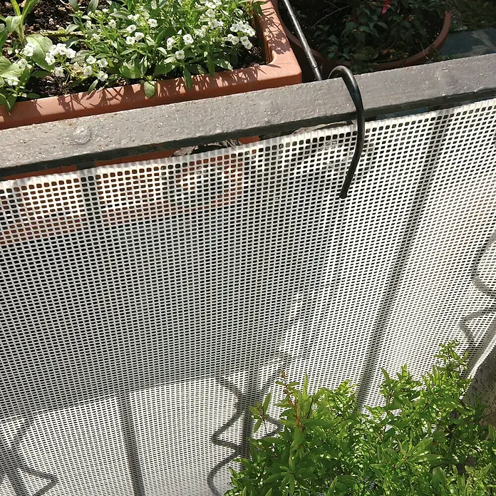 Tenax Malla protectora Quadra 05 - L x Al: 5 x 1 m, Blanco - Barrera de malla plástica blanca montada en barandilla de balcón, protegiendo plantas en macetas.