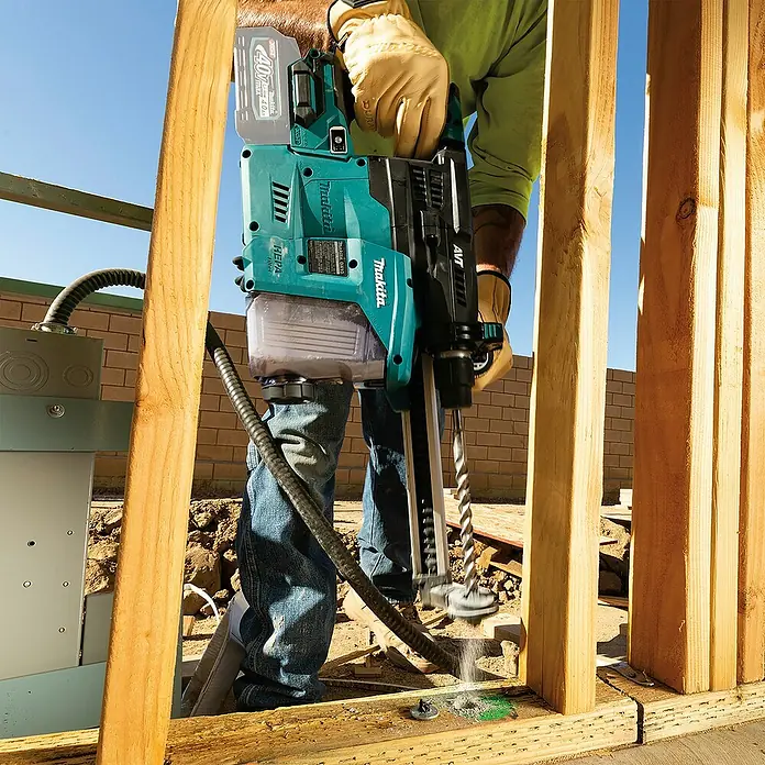 Makita XGT 40V max. Akku-Kombihammer HR008GZ - 40 V, Ohne Akku, 3,9 J - Eine Person bohrt mit einem türkis-schwarzen Makita Bohrhammer mit Staubabsaugung in einen Holzbalken.