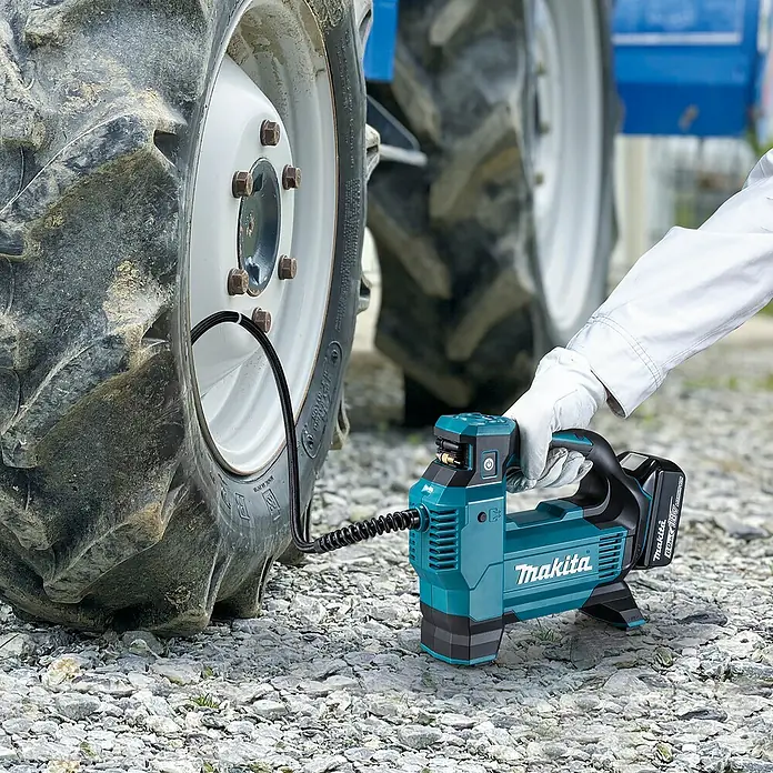 Makita LXT 18V Compresor de batería DMP181Z - 18 V, Sin batería, 11,1 bar - Compresor de aire Makita turquesa/negro inflando un neumático de tractor, sostenido por una mano enguantada.