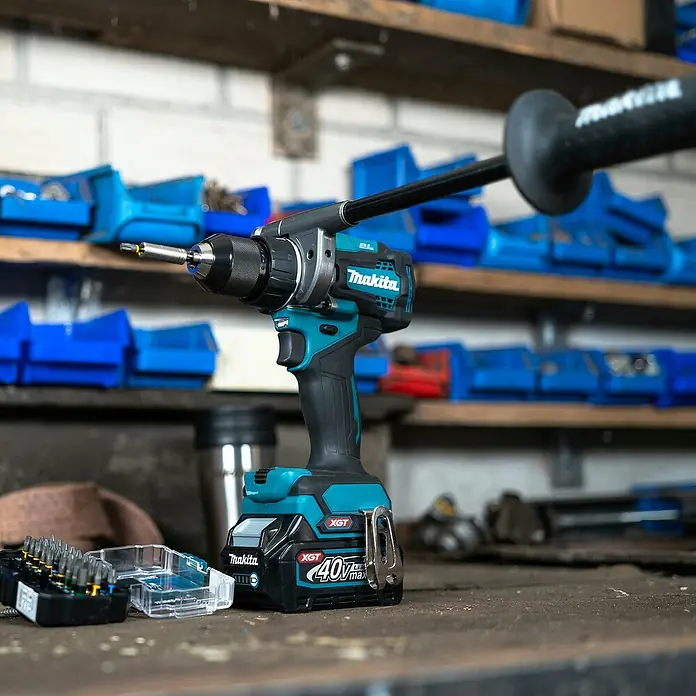 Makita XGT 40V max. Taladro atornillador de batería DF001GZ - 40 V, Sin batería - Taladro inalámbrico Makita 40V Max XGT turquesa y negro con empuñadura auxiliar y juego de brocas en un taller.