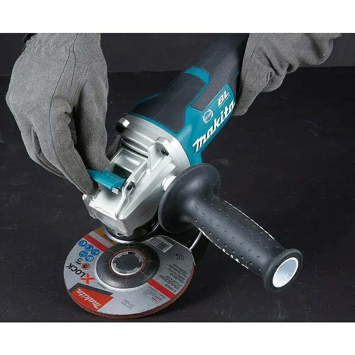 Makita LXT 18V Akku-Winkelschleifer DGA519Z - 18 V, Ohne Akku, Leerlaufdrehzahl: 3.000 U/min - 8.500 U/min - Behandschuhte Hände installieren eine rote und silberne Makita X-LOCK Schleifscheibe auf einem teal-schwarzen Makita Winkelschleifer.