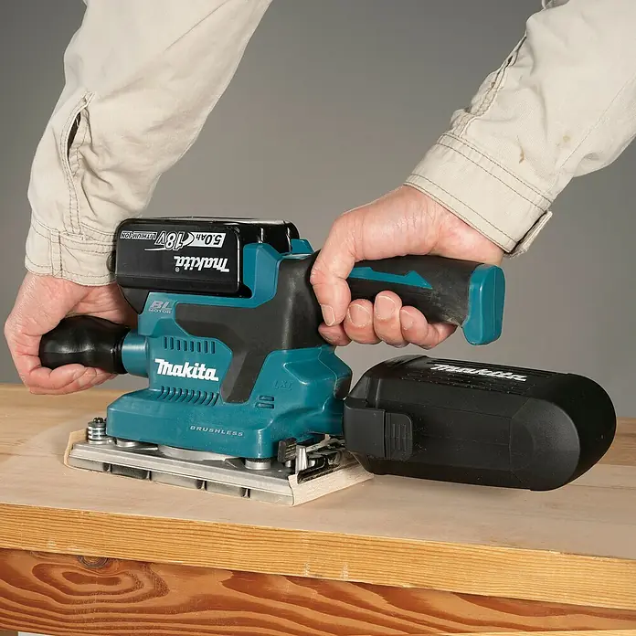 Makita LXT 18V Akku-Schwingschleifer DBO382Z - 18 V, Ohne Akku - Türkis-schwarzer Makita Akku-Schwingschleifer, von Händen gehalten, schleift eine Holzoberfläche.