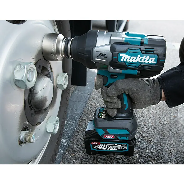 Makita XGT 40V max. Akku-Schlagschrauber TW001GZ - 40 V, Ohne Akku - Eine Person mit Arbeitshandschuhen verwendet einen türkisfarbenen und schwarzen Makita 40V max Akku-Schlagschrauber, um eine Radmutter am Fahrzeugrad zu befestigen.