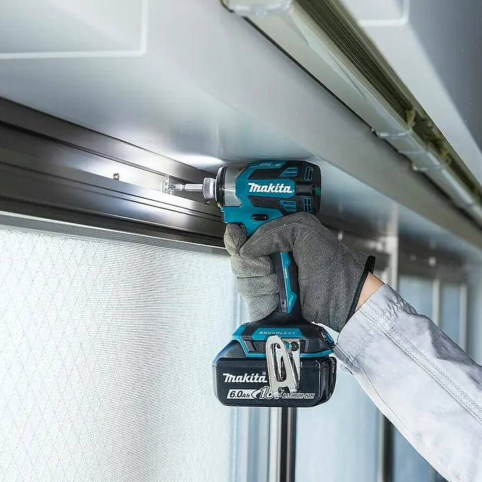 Makita LXT 18V Akku-Schlagschrauber DTD173Z - 18 V, Ohne Akku - Makita Schlagschrauber mit 6,0Ah 18V Akku, von einer behandschuhten Hand gehalten, befestigt eine Schraube in einem Rahmen.