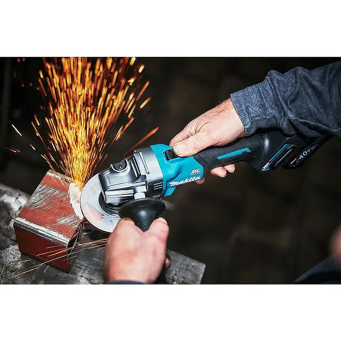 Makita XGT 40V max. Akku-Winkelschleifer GA008GM201 - 2 Akkus, 4 Ah, Durchmesser Scheibe: 125 mm - Makita Winkelschleifer (türkis, schwarz, silber) schleift Metall, erzeugt helle orange Funken.