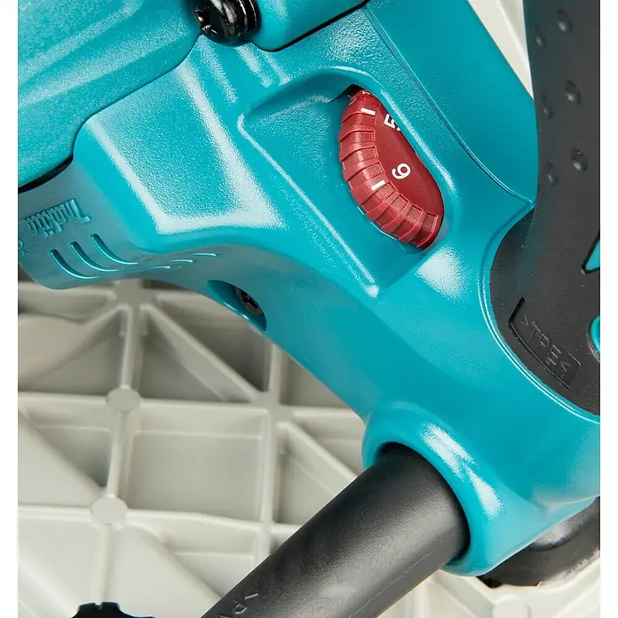 Makita Tauchsäge SP6000J1 mit Makpac und Führungsschiene - 1.300 W, 6.400 U/min - Nahaufnahme eines aquafarbenen Elektrowerkzeuggehäuses mit strukturierter Oberfläche, rotem Drehzahlregler und schwarzem Kabel.