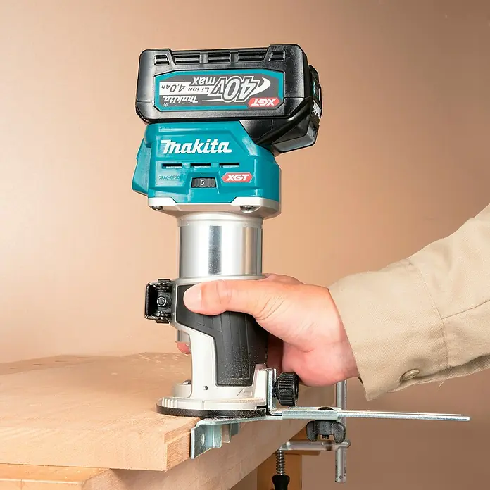 Makita XGT 40V max. Akku-Multifunktionsfräse RT001GZ10 - 40 V, Ohne Akku, Leerlaufdrehzahl: 10.000 U/min - 31.000 U/min - Person benutzt Makita 40V XGT Akku-Oberfräse mit 4.0Ah Akku zum Fräsen einer Holzkante mit Kantenführung.