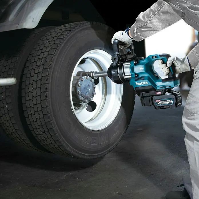 Makita XGT 40V max. Akku-Schlagschrauber TW010GZ - 40 V, Ohne Akku, 3.150 Nm - Person benutzt einen türkis-schwarzen Makita XGT 40V Schlagschrauber an einem großen LKW-Rad.