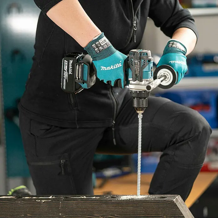 Makita LXT 18V Akku-Schlagbohrschrauber DHP492RTJ - 18 V, 2 Akkus, 5 Ah, 130 Nm - Person mit tealfarbenen Makita-Handschuhen nutzt Makita-Bohrschrauber mit 18V-Akku, um lange Schraube in Holzbalken zu treiben.