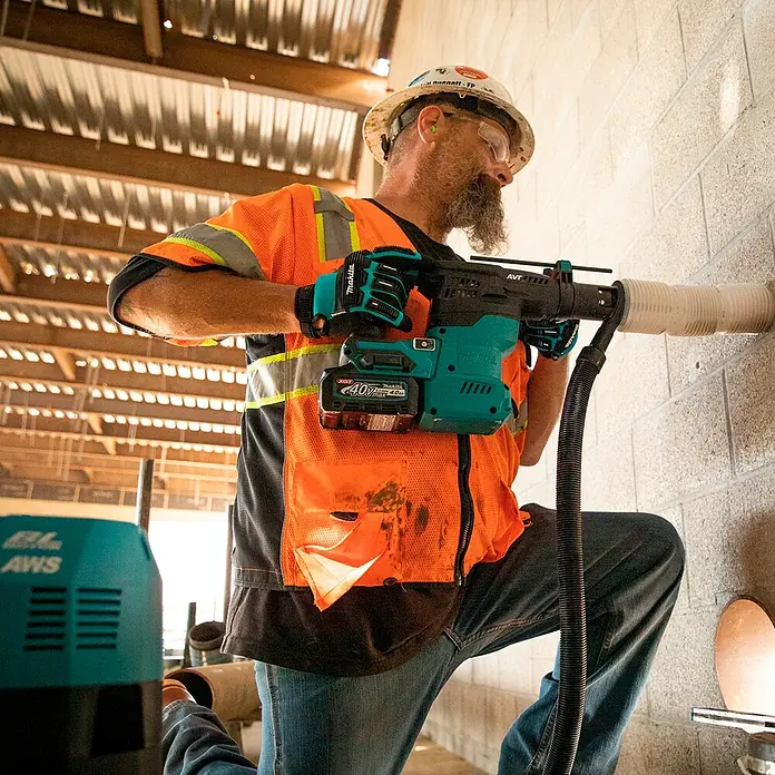Makita XGT 40V max. Akku-Kombihammer HR009GZ - 40 V, Ohne Akku, 3,9 J - Arbeiter benutzt einen teal-schwarzen Makita Bohrhammer mit 4.0Ah Akku zum Bohren in eine Betonwand, mit Staubabsaugung.