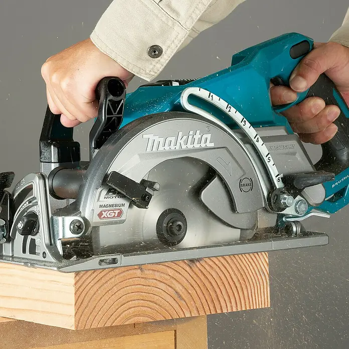 Makita XGT 40V max. Akku-Handkreissäge RS001GZ - 40 V, Ohne Akku, Durchmesser Sägeblatt: 185 mm, 6.400 U/min - Eine Person sägt mit einer türkis-silbernen Makita Kreissäge ein Stück Holz, Sägespäne fliegen.