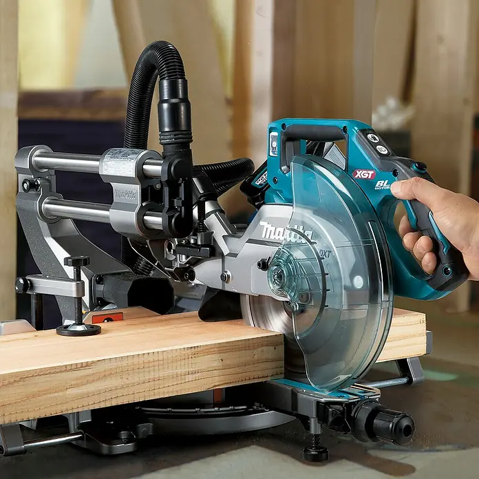 Makita XGT 40V max. Akku-Kapp- & Gehrungssäge LS002GZ01 - 40 V, Ohne Akku, 4.800 U/min - Türkis-schwarze Makita XGT Akku-Kapp- und Gehrungssäge, von einer Hand bedient, sägt ein Holzbrett.
